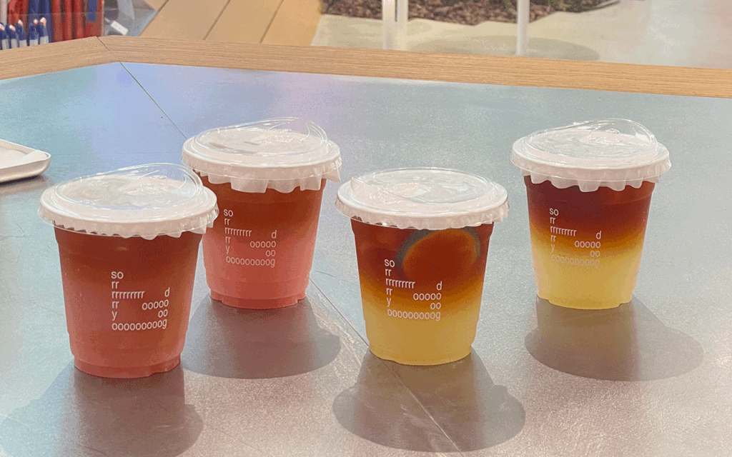 Disposable iced coffee cups – YamiPak Coffee PET cups with flat lids – clear cold drinks – indoor café counter lineup, eye-level angle