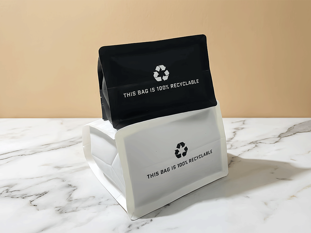 Black and white recyclable coffee bags stacked together on a tabletop
