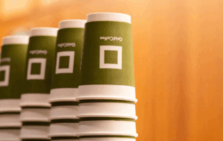 Stacked disposable paper cups with custom design on a counter.