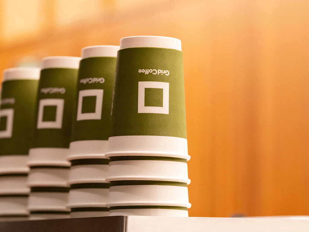 Are-Disposable-Coffee-Cups-Recyclable-3 Stacked disposable paper cups with custom design on a counter.