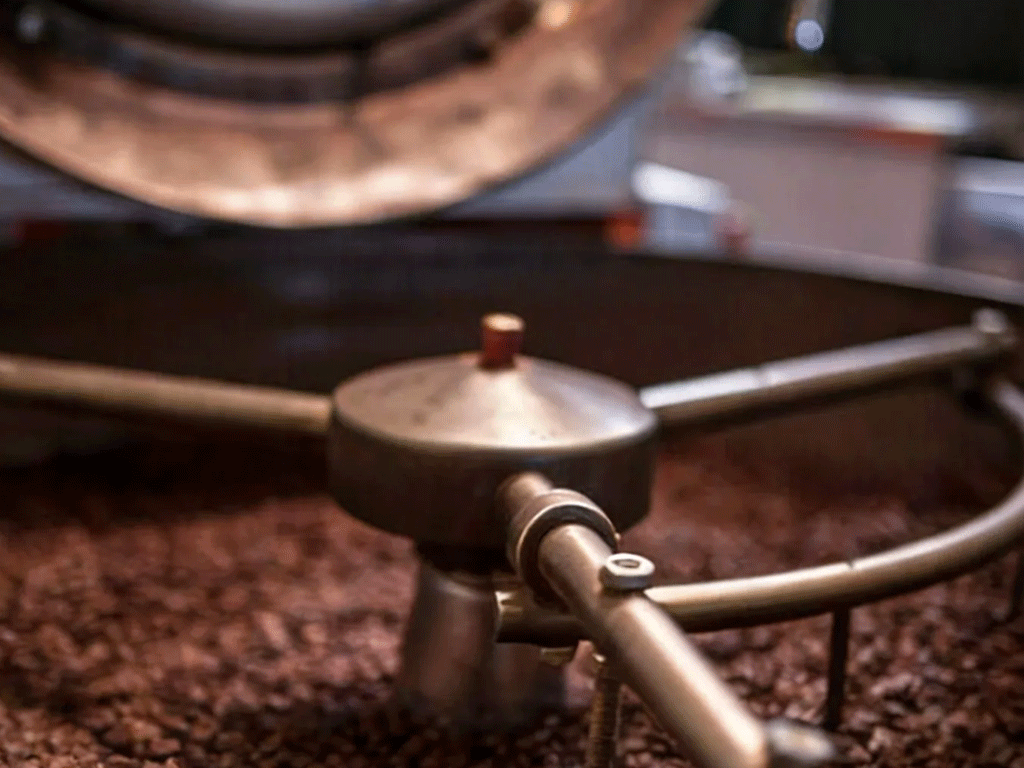 Coffee beans roasting in a drum roaster, showing the roasting stage of coffee production