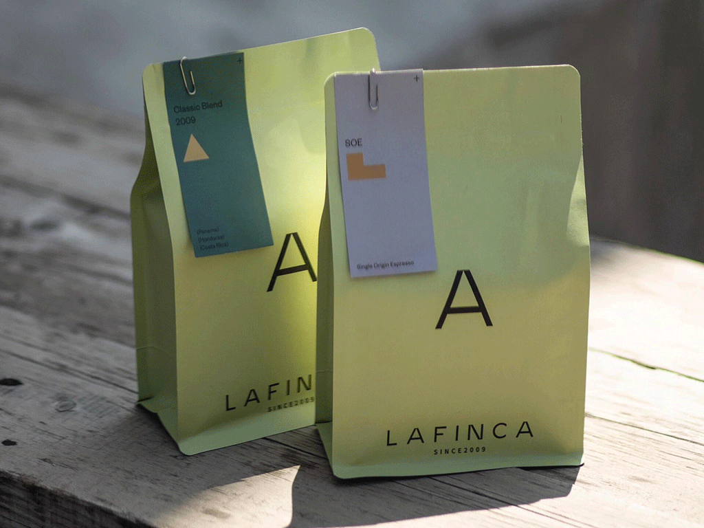 Two green custom coffee bags on a wooden surface, illustrating coffee packaging for reducing carbon footprint