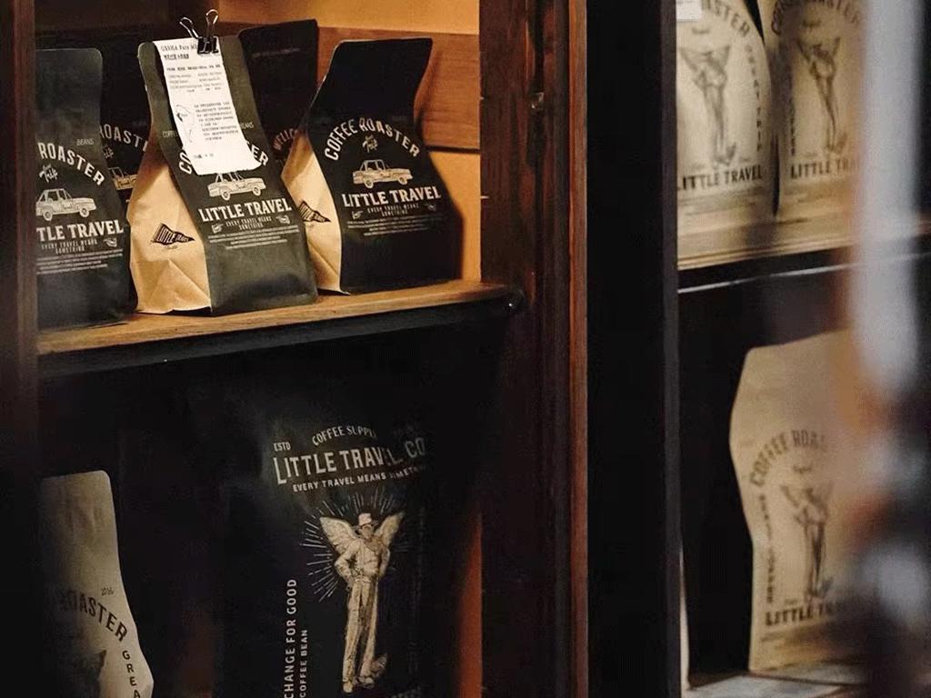 coffee-bag-design-tips-for-small-roasters-1 Black and kraft flat bottom coffee bags with printed logos neatly arranged on wooden shelves, showcasing stylish packaging for small roasters.