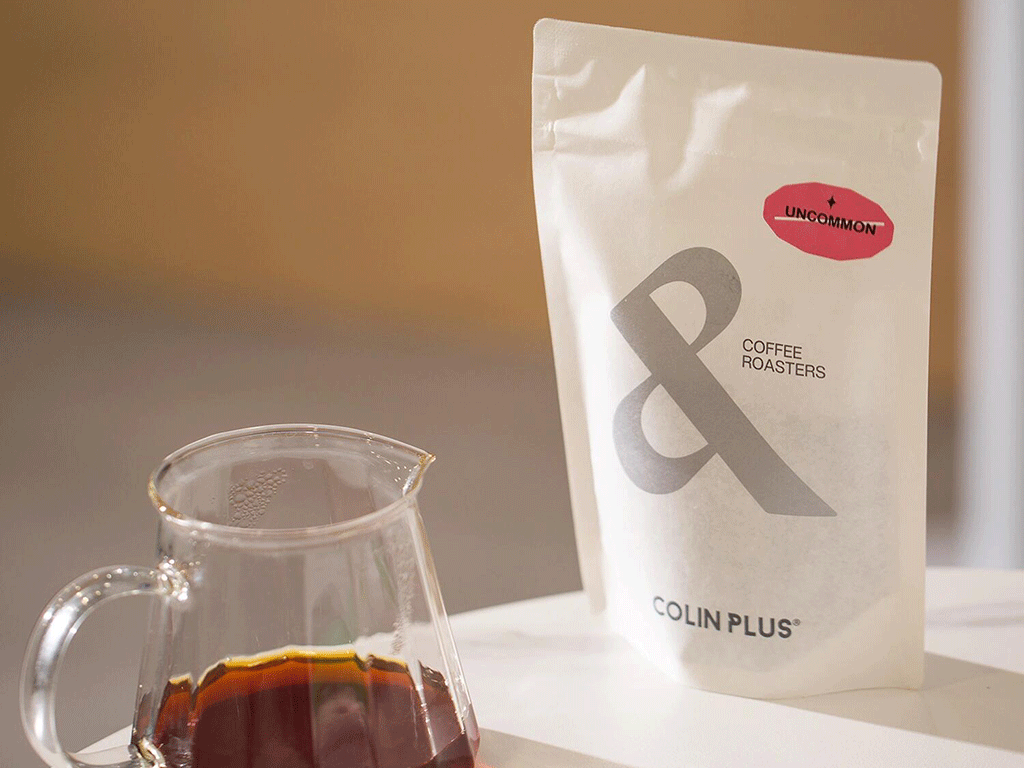 specialty coffee packaging displayed beside brewed coffee in a glass server