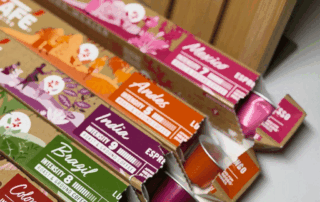 Five open coffee capsule boxes fanned out to show single-origin varieties including Colombia, Brazil, India, Andes, and Mexico, each with a colour-coded design and intensity rating.