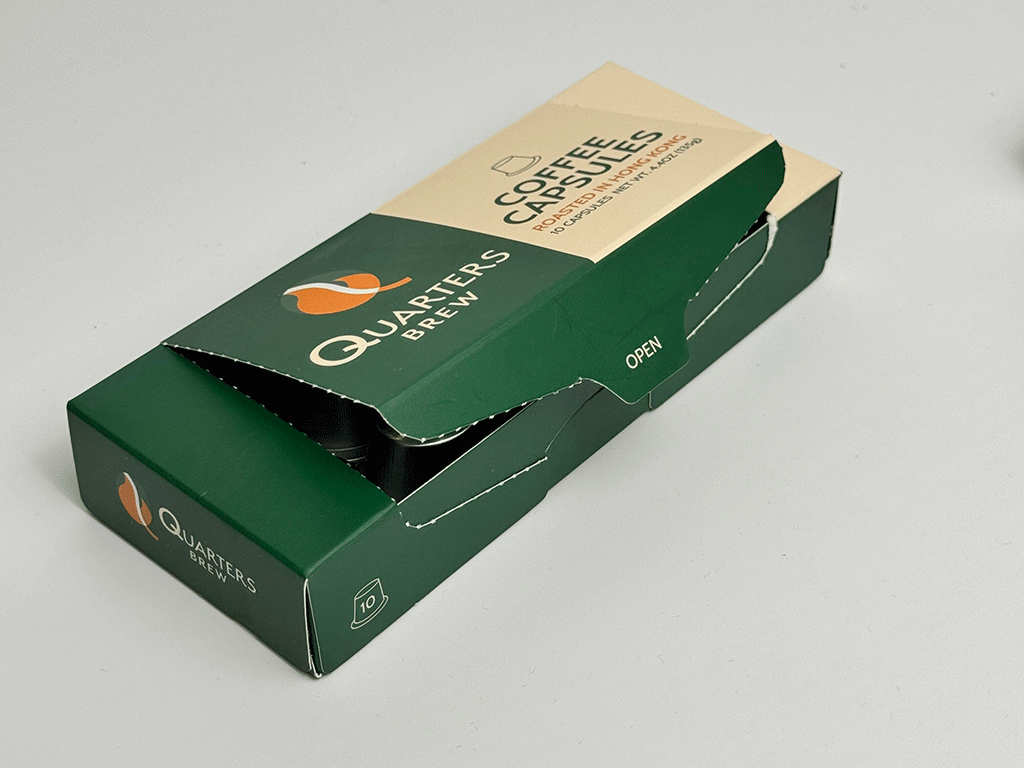 A coffee capsule box showing the front and top panels, with the brand logo, "Coffee Capsules – Roasted in Hong Kong", capsule count icon, and a pull-open tab labelled "Open".