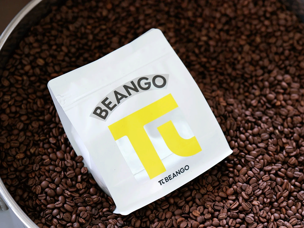 Are_coffee_bags_getting_smaller_1 Small white coffee bag displayed on roasted coffee beans to illustrate changing specialty coffee packaging sizes