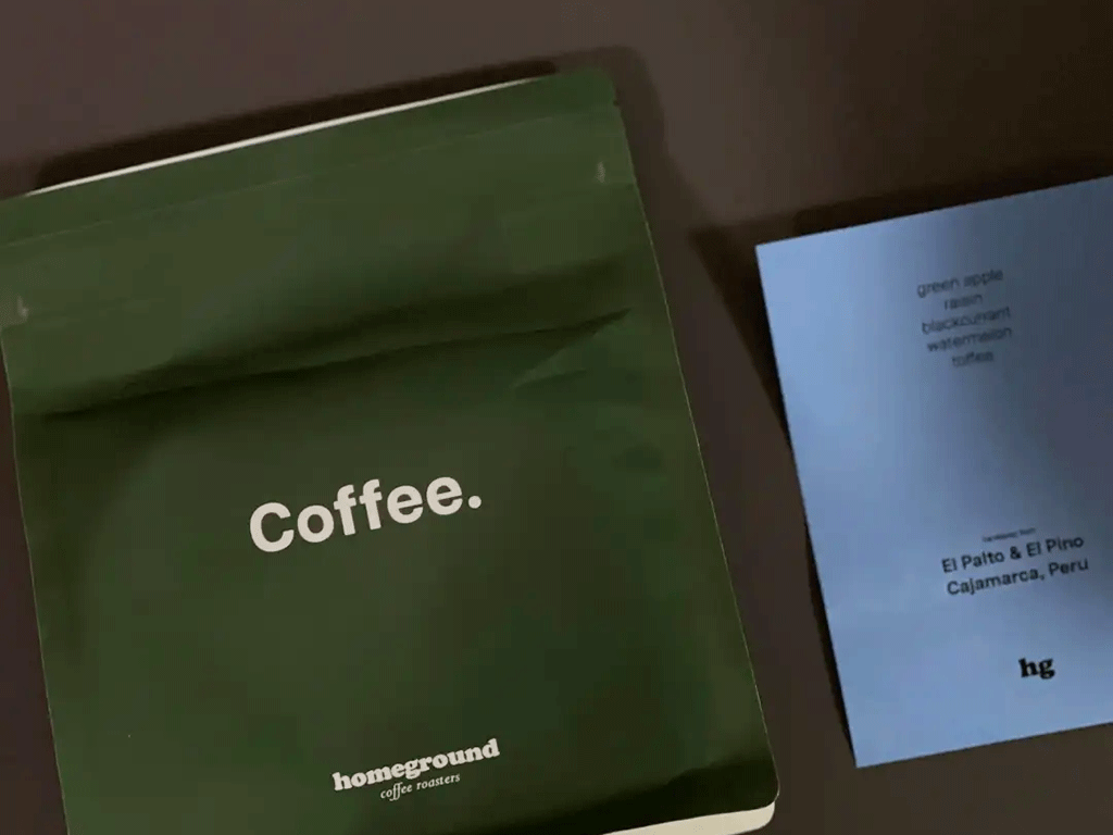 Green specialty coffee bag displayed beside a blue coffee tasting card with origin and flavour details