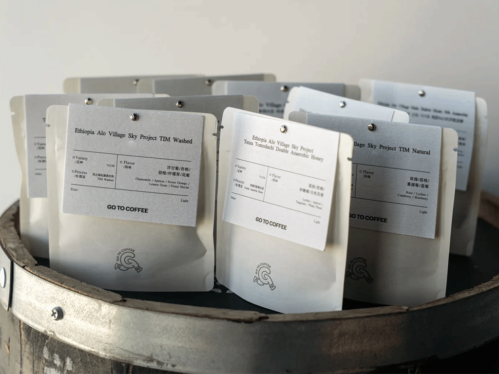 Small specialty coffee bags displayed with coffee tasting cards showing origin, processing method, and flavour notes