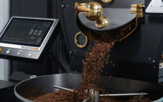 Freshly roasted coffee beans being poured from a commercial drum roaster, illustrating the roasting process and Rate of Rise control for coffee roasters