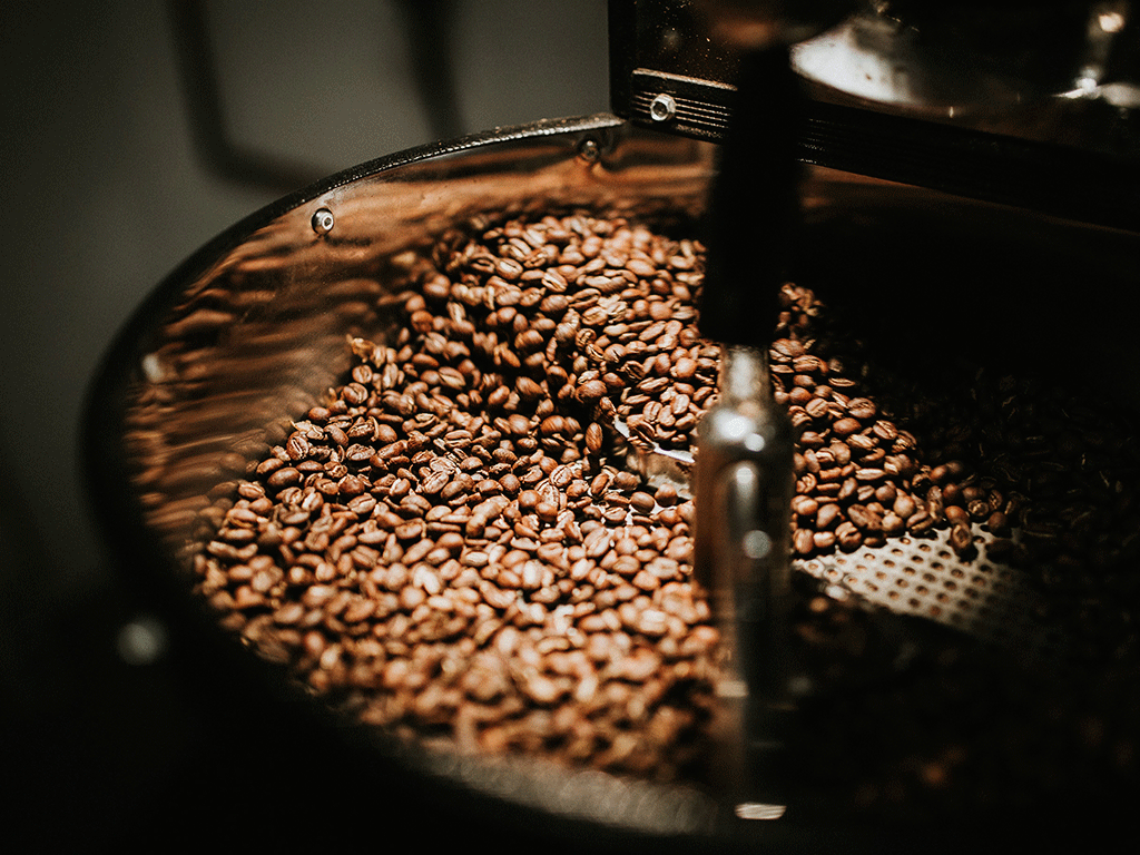 Close-up of roasted coffee beans rotating in a roasting drum, highlighting heat transfer and bean development during the roasting process