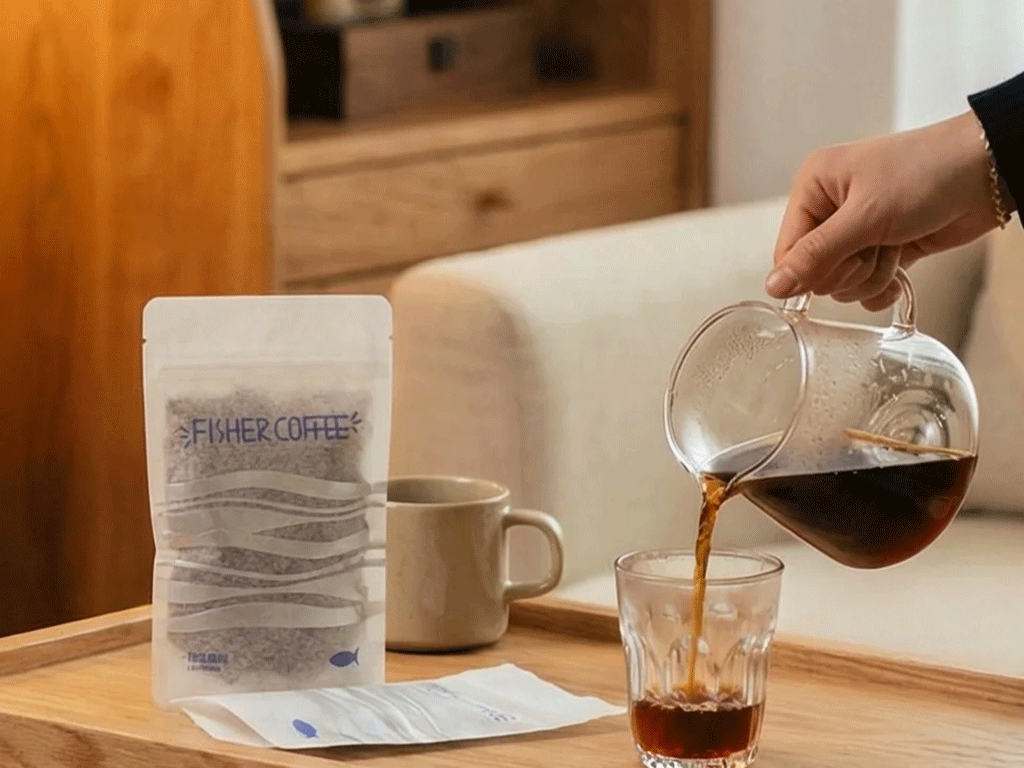 Rice paper coffee bag displayed on a wooden tray beside a glass of freshly brewed pour-over coffee