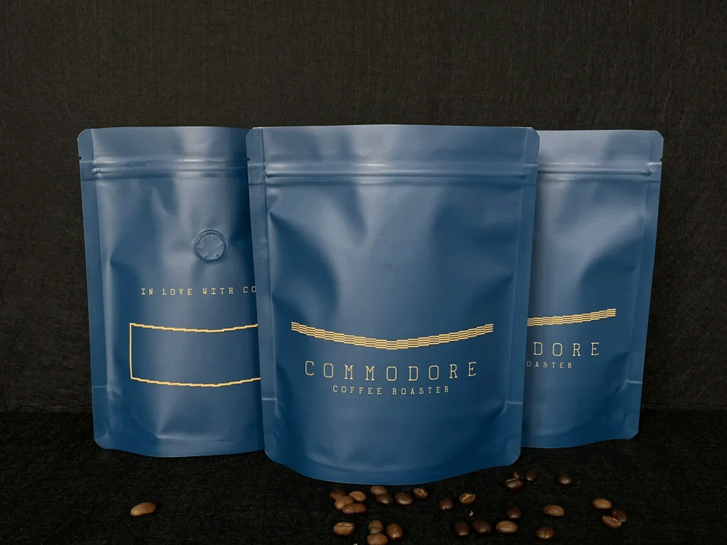 Matte blue stand up coffee bags with coffee beans on a dark background