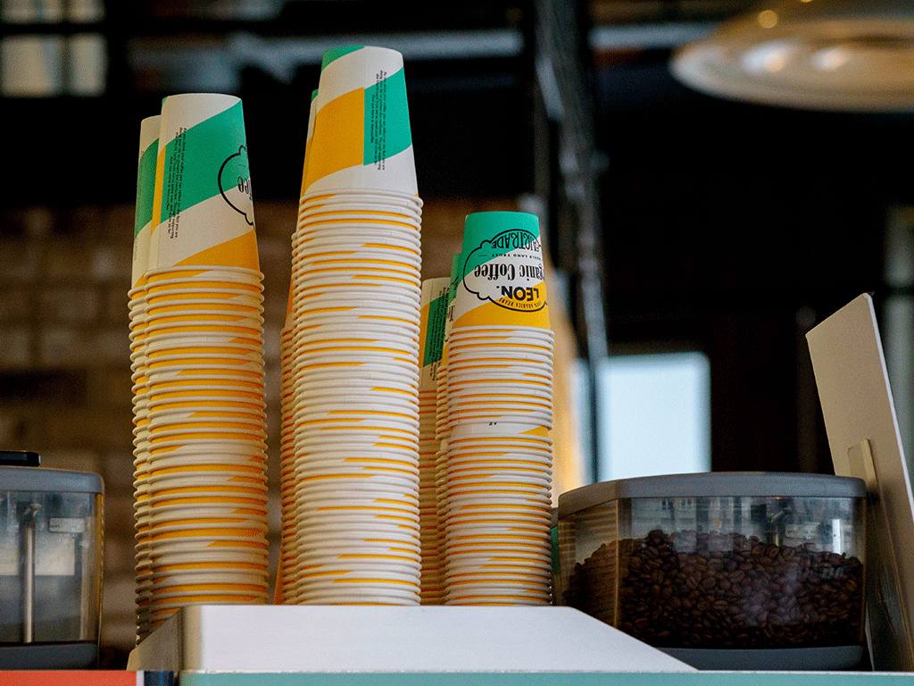 Are_Single_Use_Coffee_Cups_Recyclable_1 Stacks of paper hot coffee cups with custom branding and waterproof linings displayed on a counter.
