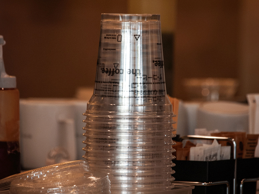 A stacked pile of clear plastic cold drink cups made from recyclable materials like PET or PP.