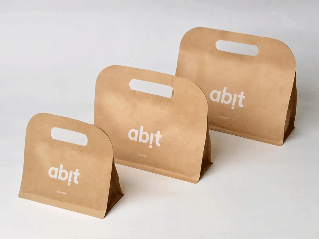 Three kraft stand-up coffee bags with die-cut handles in different sizes