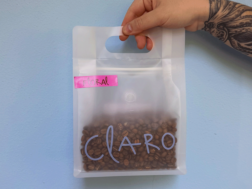 Hand carrying a frosted coffee bag with a built-in handle filled with roasted coffee beans