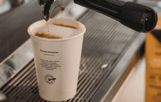 Takeaway coffee cup being filled with espresso from a commercial coffee machine