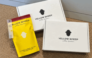 Yellow coffee bag placed beside two white coffee subscription boxes