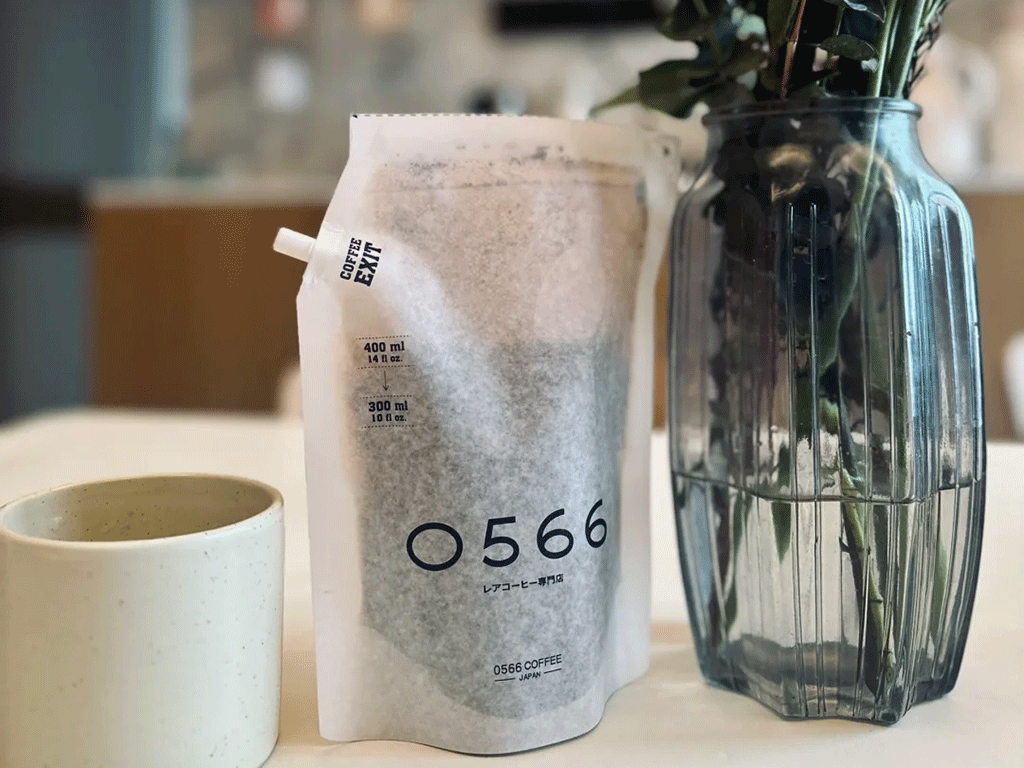 Custom white coffee brewing bag with a white spout beside a coffee cup